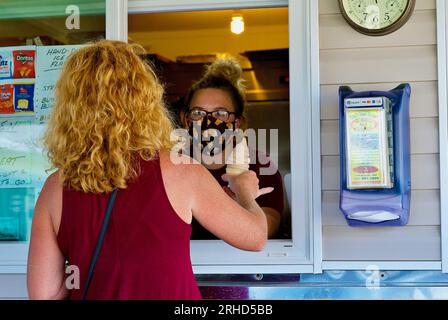 Tangier Island, Virginia, USA - 21. Juni 2020: Ein Kunde akzeptiert einen Eiskegel von einem maskierten Mitarbeiter an einem Eisdielen an der Main Street. Stockfoto