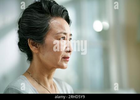 Kopfschuss von einer traurigen asiatischen alten Frau, Seitenansicht Stockfoto