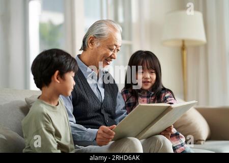 Seniorengroßvater aus Asien hat sich mit zwei Enkeln zu Hause amüsiert Stockfoto