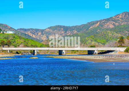 Blick auf den Abschnitt Pacific Coast Highway von der Malibu Lagune aus von einem niedrigen Aussichtspunkt vor einem malerischen Berghintergrund. Stockfoto