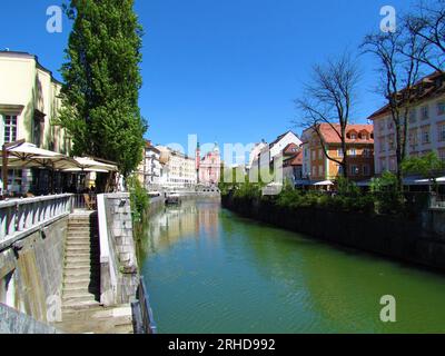 Der Fluss Ljubljanica fließt durch die slowenische Stadt Ljubljana und die Franziskanerkirche der Verkündigung und spiegelt die Gebäude im ri wider Stockfoto