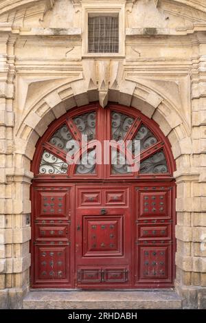 Vertikaler Blick auf die alte rote Holztür und die klassische Steinveranda im historischen Stadtzentrum von Montpellier, Frankreich Stockfoto