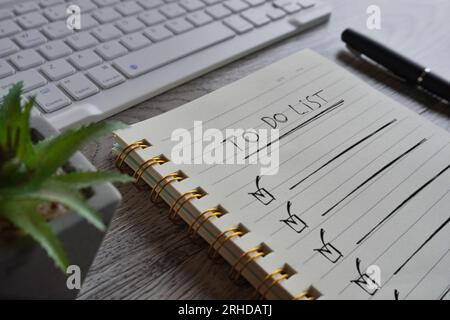 Nahaufnahme des Notizbuchs mit einer AUFGABENLISTE auf der Tabelle. Stockfoto