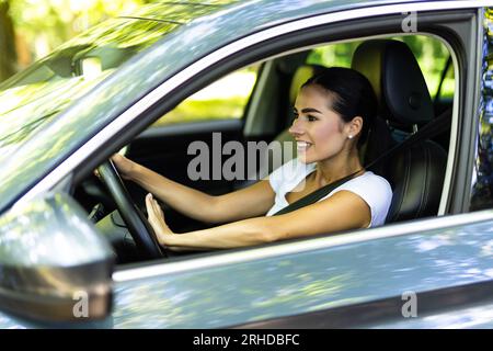 Junge hübsche Frau drückt die Hupe-Taste, während sie ein Auto durch die Straße fährt. Stockfoto