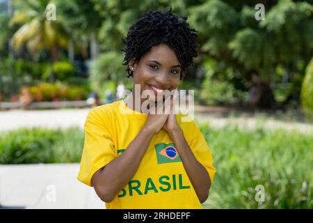 Schöne junge Frau aus Brasilien mit gelbem Fußballtrikot im Sommer im Freien Stockfoto