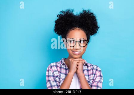 Foto eines bezaubernden, netten, positiven Mädchens gekleidetes kariertes Hemd Hände unter dem Kinn träumt aussehen leer isoliert auf blauem Hintergrund Stockfoto