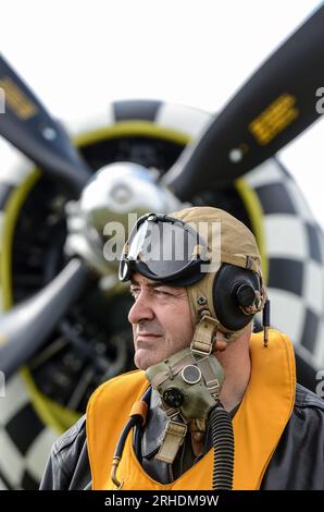 Reenactor gekleidet in Epoche 2. Weltkrieg USAAF Flugkostüm mit P-47 Thunderbolt Flugzeug. Fluganzug mit Rettungsweste Typ B-3, Helm, Maske Stockfoto