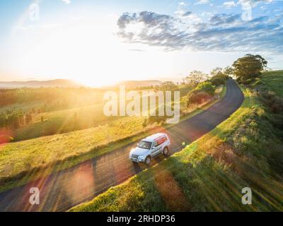 Reiseversicherungskonzept mit Auto auf Landstraße Fahren bei Sonnenuntergang auf Roadtrip Abenteuer Stockfoto