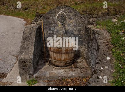 Ein alter historischer Trinkwasserbrunnen aus Stein im Dorf Trava im Distrikt Lauco, Provinz Udine, Friaul-Julisch Venetien, Nordost-Italien Stockfoto