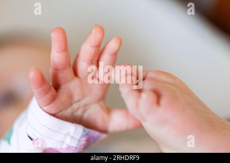 Nahaufnahme von Babyfingern, die an den Zehen greifen Stockfoto