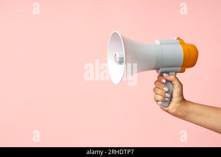 Megaphon-Lautsprecher in Frauenhänden auf rosafarbenem Hintergrund mit Kopierraum Stockfoto