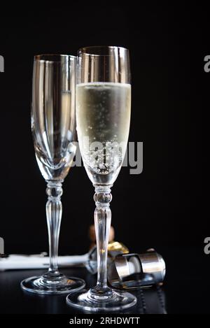 Zwei Champagnergläser auf schwarzem Hintergrund mit Öffner und Stopper Stockfoto