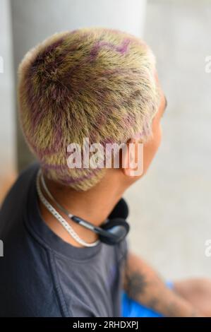 Rückansicht eines unbekannten Mannes mit gefärbtem Haar und Tätowierung auf der Hand, der zu Hause im Lichtzimmer steht Stockfoto