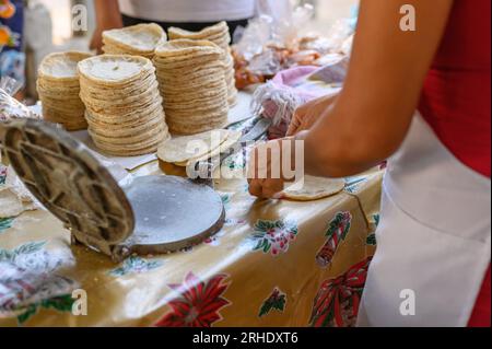 Seitenansicht der anonymen weiblichen Kochtortilla mit Pressmaschine auf dem Verkaufsstand Stockfoto