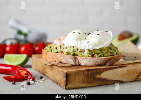 Köstliches Sandwich mit Guacamole, Garnelen und Spiegelei auf hellgrauem Tisch, Nahaufnahme Stockfoto