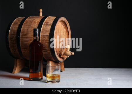 Fass mit Hahn, Flasche und Glas leckerem Whiskey auf hellgrauem Holztisch, Platz für Text Stockfoto