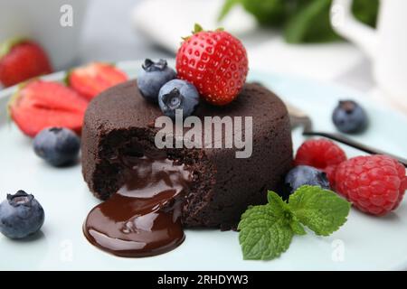 Köstliche Schokoladenfondant, Beeren und Minze auf dem Teller, Nahaufnahme Stockfoto