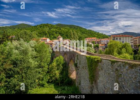 Die alte mittelalterliche Brücke, die den Fluss Ter in Sant Joan de les Abadesses überquert, mit der Stadt im Hintergrund (Ripollès, Girona, Katalonien, Spanien) Stockfoto