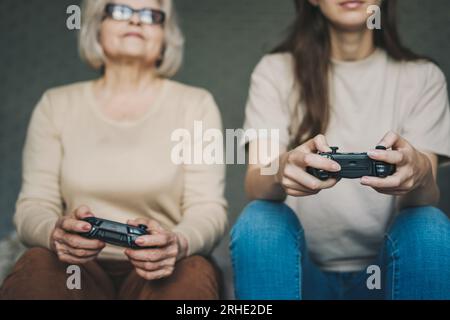 Zwei aufgeregte Frauen, die ein Videospiel spielen, das Gamepad in der Hand halten, auf dem Sofa sitzen und lustige Wettkämpfe erleben. Wir verbringen das Wochenende zusammen. Stockfoto