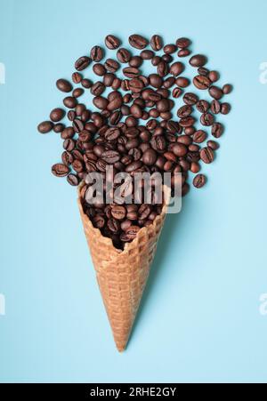Waffelkonus mit Kaffeebohnen auf blauem Hintergrund – Nahaufnahme Stockfoto
