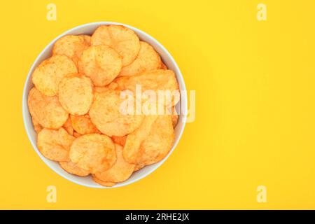 Behälter mit Kartoffelchips auf gelbem Hintergrund. Fast Food-Konzept – Nahaufnahme Stockfoto