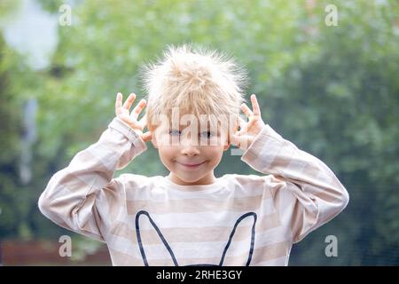 Süße kleine Jungen mit statischen electricy Haar, in seiner komischen Porträt im Freien auf einem Trampolin genommen Stockfoto