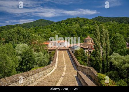 Die alte mittelalterliche Brücke, die den Fluss Ter in Sant Joan de les Abadesses überquert, mit der Stadt im Hintergrund (Ripollès, Girona, Katalonien, Spanien) Stockfoto