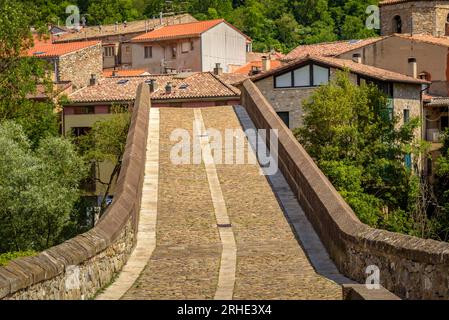 Die alte mittelalterliche Brücke, die den Fluss Ter in Sant Joan de les Abadesses überquert, mit der Stadt im Hintergrund (Ripollès, Girona, Katalonien, Spanien) Stockfoto