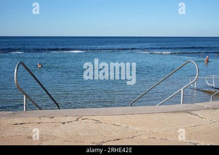 Zwei ältere Schwimmer im Shelly Beach Ocean Pool mit großem australischen blauen Himmel, blauem Ozean Pool und offenem Meer dahinter, Cronulla, Sydney Stockfoto