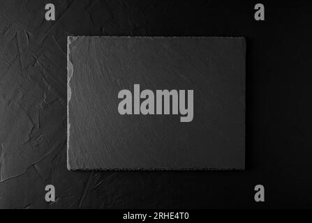 Schwarze Granitplatte auf schwarzem Betonhintergrund. Hintergrund- und Texturkonzept Stockfoto