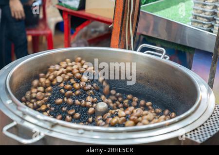 Braten von Kastanien im Ofen, geröstet auf dem Street Food Market. Stockfoto