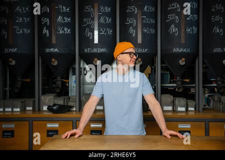 Freundlicher Barkeeper im Inneren des modernen Coffeeshops mit einer großen Auswahl an Kaffeebohnen. Stockfoto