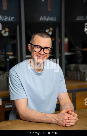 Freundlicher Barkeeper im Inneren des modernen Coffeeshops mit einer großen Auswahl an Kaffeebohnen. Stockfoto