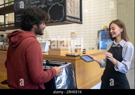 Ein männlicher Kurier mit Lockenhaar nimmt Befehle aus dem Café entgegen Stockfoto