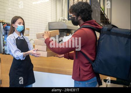 Ein männlicher Kurier mit Lockenhaar nimmt Befehle aus dem Café entgegen Stockfoto