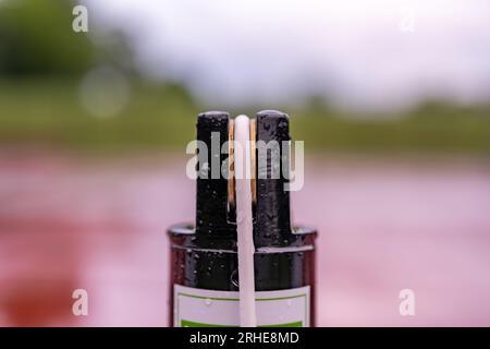 Oberseite des schwarzen Tennisplatznetzpfostens mit weißem Kabel und Messing-Spannführung. Stockfoto