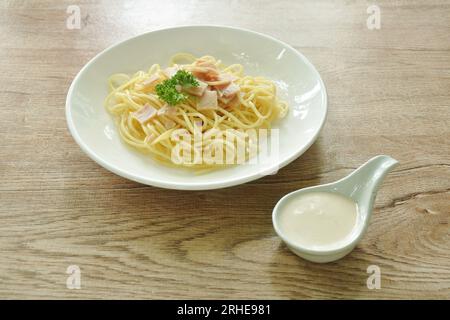 Gedämpfte Spaghetti mit weißer Cabonara-Sahnesauce, auf dem Schweineschinken in Scheiben geschnitten wird Stockfoto