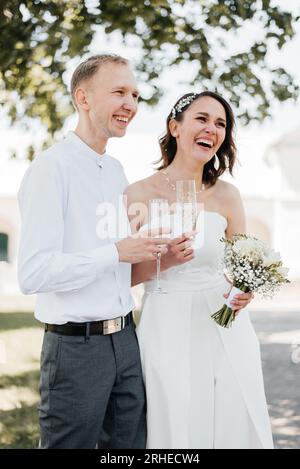 Glückliches, lächelndes Hochzeitspaar mit einem Glas Champagner in der Hand. Braut und Bräutigam. Brautpaare genießen einen romantischen Moment zusammen während Stockfoto