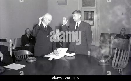 1950er, historisch, in einem Raum, stehen an einem großen Tisch, zwei Männer mit erhobenen Händen, einer liest aus einem Buch, der otjher legt ein Versprechen oder einen Eid ab, den er einhalten wird, Columbus, Ohio, USA. Hochrangige Polizisten, die im Raum sitzen, beobachten die Prozedur. Worte an der Tür, Büro der Kommissare. Stockfoto