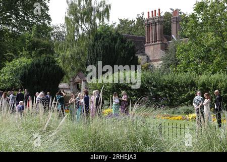 Eine Hochzeitsgesellschaft versammelt sich in Southover Grange Gardens, nachdem sie das Kasse hinter den Eibenbäumen besucht hat. Stockfoto