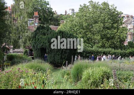 Eine Hochzeitsgesellschaft versammelt sich in Southover Grange Gardens, nachdem sie das Kasse hinter den Eibenbäumen besucht hat. Stockfoto