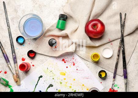 Papierbogen mit Malstrichen, Tuch und Pinseln auf leichtem Grunge-Hintergrund Stockfoto
