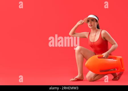 Rettungsschwimmerin mit Rettungsboje auf rotem Hintergrund Stockfoto