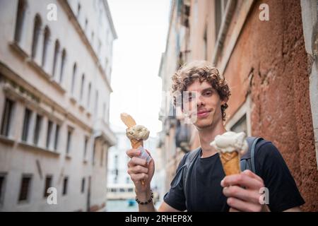Ein Tourist hält zwei Eiscremes und wählt das Eis, das er während seines Urlaubs in Venedig essen möchte Stockfoto