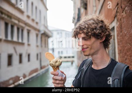 Ein Tourist isst im Sommer während seines Urlaubs in Venedig Eis Stockfoto