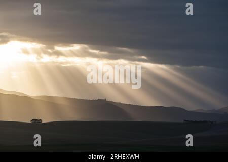 Sonnenstrahlen brechen am Ende des Tages in der Ferne durch Wolken Stockfoto