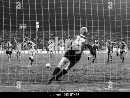 Krefeld, Deutschland, Europapokal der Pokalsieger Bayer Uerdingen (GER) vs. Dynamo Dresden (DDR) 7-3 am 19. 03. 1986 in der Grotenburg - Kampfbahn in Krefeld. Wolfgang FUNKEL (Bayer Uerdingen ) 3.v.li.- verwandelt einen Handelfmeter in der 79. Spielminute zur 6-3 FŸhrung der Uerdinger, der das Grade des Halbfinale bedeutete. Ersatztorwart Jens RAMME ( Dynamo Dresden ) RE.- war machtlos. Foto: Norbert Schmidt, Düsseldorf Stockfoto