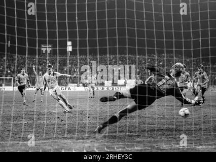 Krefeld, Deutschland, Europapokal der Pokalsieger Bayer Uerdingen (GER) vs. Dynamo Dresden (DDR) 7-3 am 19. 03. 1986 in der Grotenburg - Kampfbahn in Krefeld. Wolfgang FUNKEL (Bayer Uerdingen ) 3.v.li.- verwandelt einen Handelfmeter in der 79. Spielminute zur 6-3 FŸhrung der Uerdinger, der das Grade des Halbfinale bedeutete. Ersatztorwart Jens RAMME ( Dynamo Dresden ) RE.- war machtlos. Foto: Norbert Schmidt, Düsseldorf Stockfoto