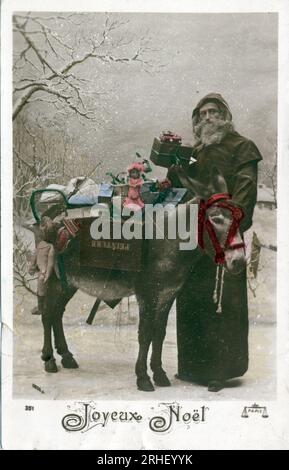 Carte de voeux pour Noel : un 'Pere Noel' avec un ane Charge de Cadeaux - carte postale datee 1907 Stockfoto