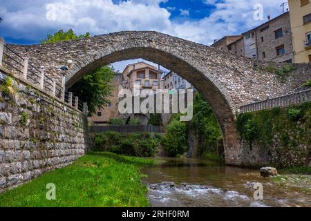 Antik und modern: Eine Straßenbrücke überspannt jetzt den Fluss Llobregat in La Pobla de Lillet in Katalonien, Spanien, neben der mittelalterlichen Pont Vell oder der alten Brücke Stockfoto